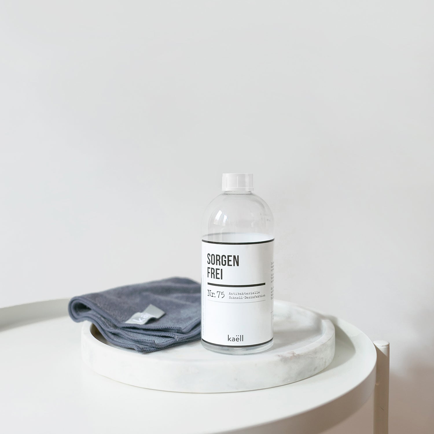 Eine Flasche antibakterielles Desinfektionsmittel mit einem grauen antibakteriellem Mikrofasertuch auf einem Tisch.